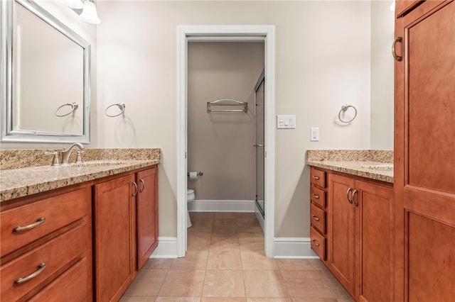 bathroom with tile patterned floors, vanity, toilet, and a shower with door