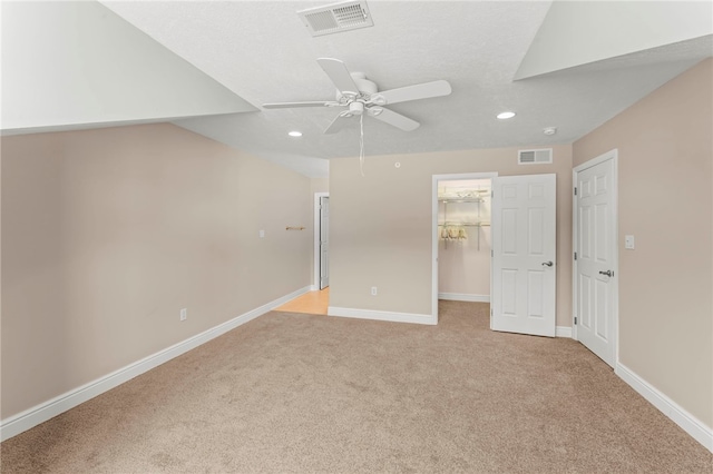 unfurnished bedroom with light carpet, a closet, a spacious closet, and ceiling fan