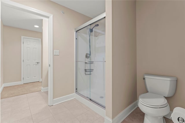 bathroom featuring tile patterned floors, toilet, and a shower with door