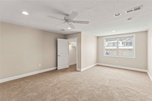 unfurnished room featuring ceiling fan, light colored carpet, and a textured ceiling