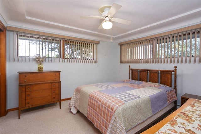 bedroom featuring ceiling fan, a raised ceiling, and light carpet