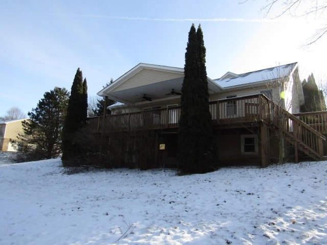 snow covered rear of property with ceiling fan and a wooden deck