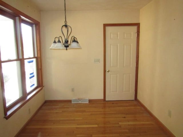 unfurnished dining area featuring wood-type flooring and a chandelier