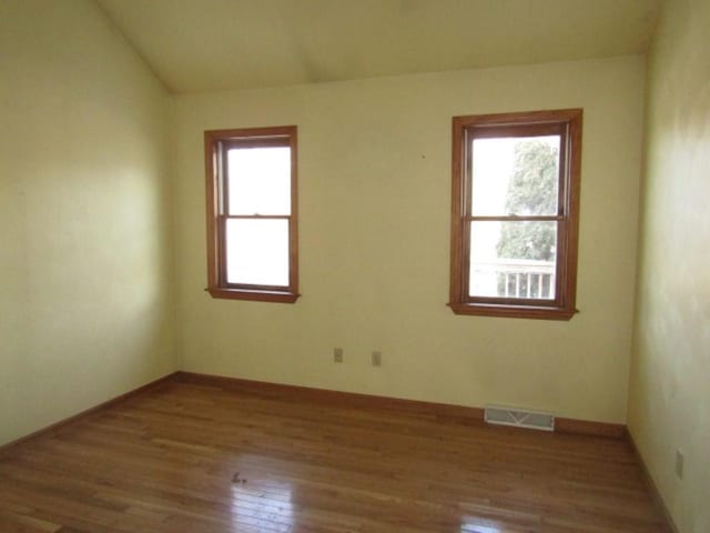 spare room with light hardwood / wood-style floors and lofted ceiling