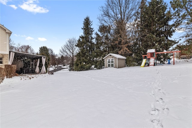 yard covered in snow with a playground and a shed