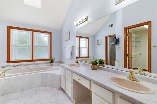 bathroom featuring tile patterned flooring, vanity, lofted ceiling with skylight, and tiled tub