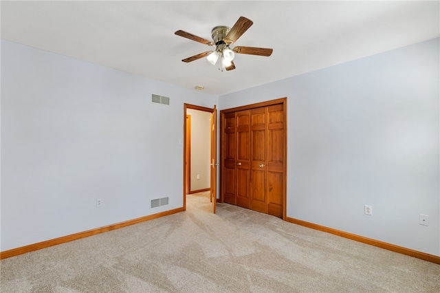 unfurnished bedroom featuring ceiling fan, light colored carpet, and a closet