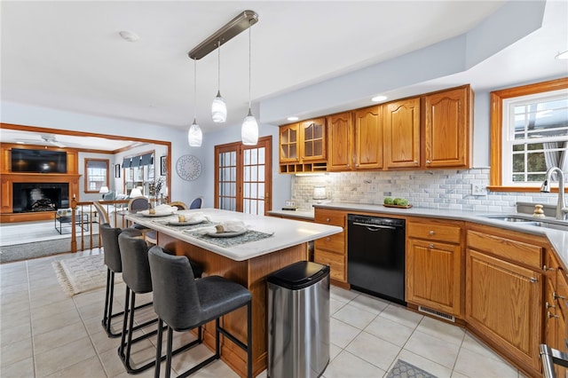 kitchen with decorative backsplash, a kitchen breakfast bar, sink, light tile patterned floors, and black dishwasher