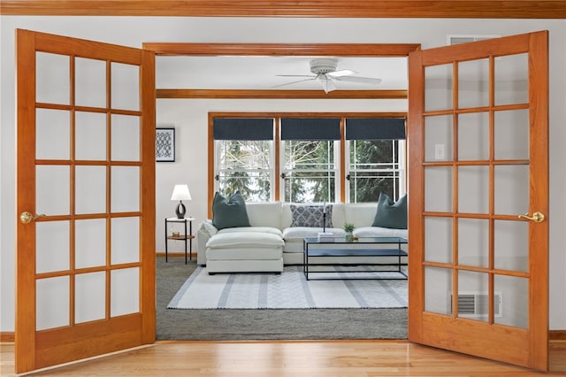 living room featuring ceiling fan, hardwood / wood-style floors, crown molding, and french doors