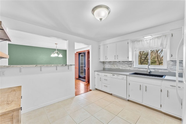 kitchen with tasteful backsplash, white dishwasher, sink, decorative light fixtures, and white cabinets