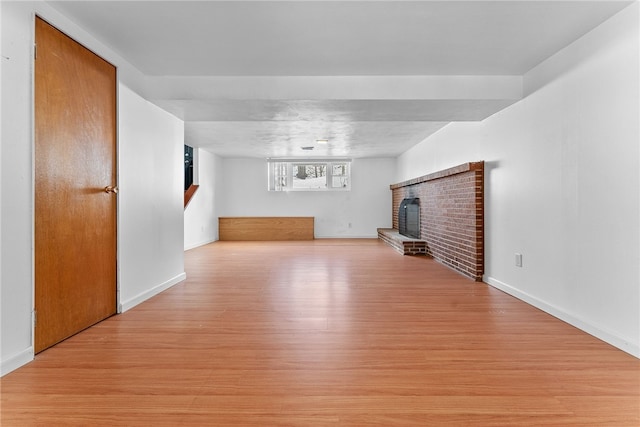 unfurnished living room with a brick fireplace and light hardwood / wood-style flooring