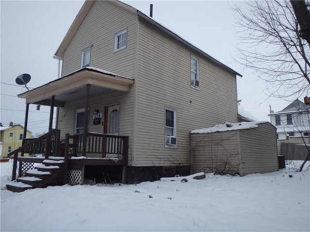 snow covered back of property with a porch