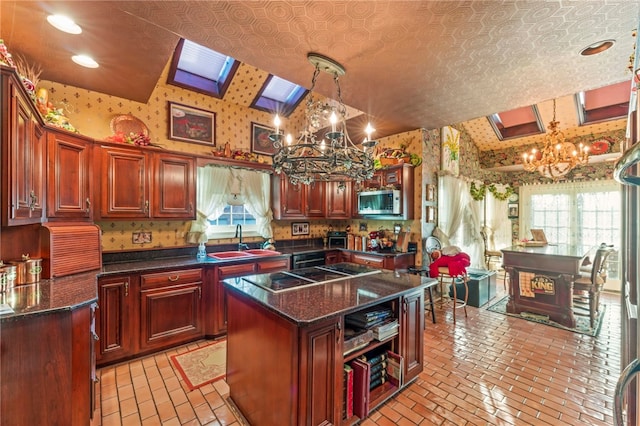 kitchen featuring lofted ceiling with skylight, sink, pendant lighting, a notable chandelier, and a center island