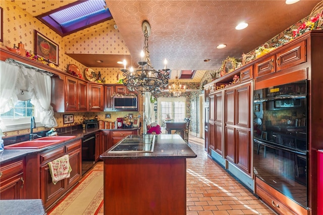 kitchen with a skylight, sink, black appliances, a notable chandelier, and a center island