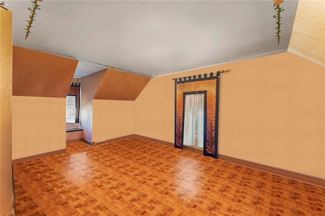 additional living space featuring parquet floors and vaulted ceiling