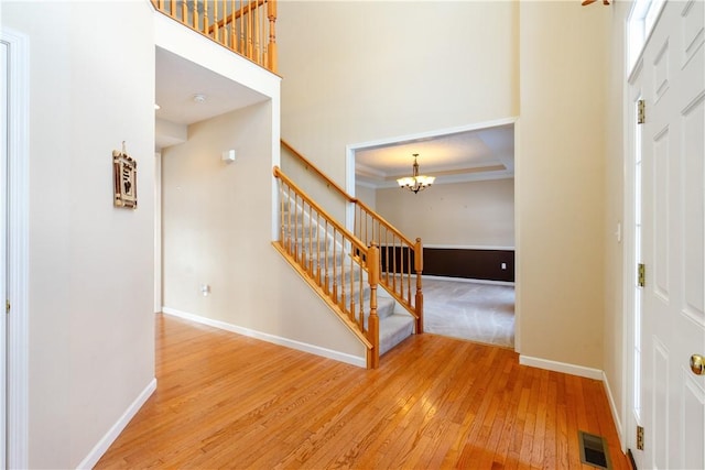 foyer entrance featuring crown molding, an inviting chandelier, a high ceiling, and hardwood / wood-style flooring