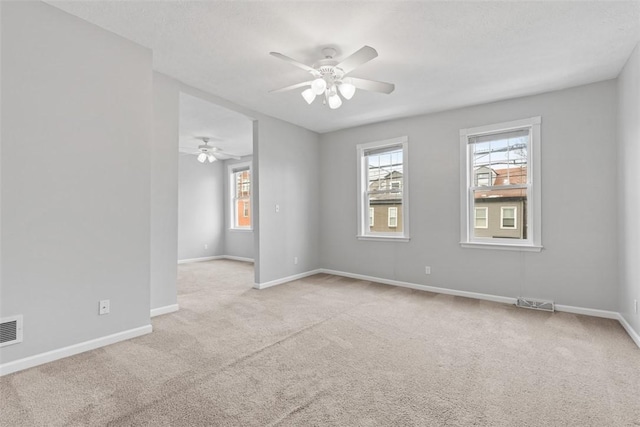 spare room with ceiling fan and light carpet