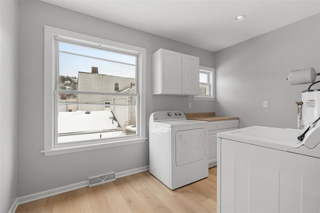 laundry area featuring a healthy amount of sunlight, cabinets, independent washer and dryer, and water heater