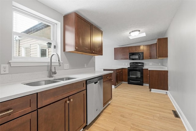 kitchen featuring sink, black appliances, a textured ceiling, and light hardwood / wood-style floors