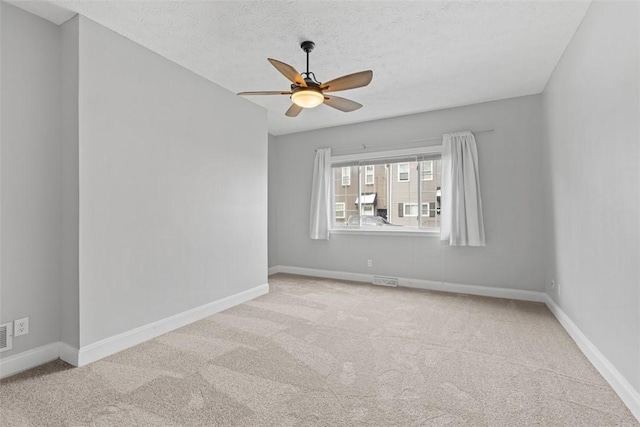 spare room featuring ceiling fan, light colored carpet, and a textured ceiling