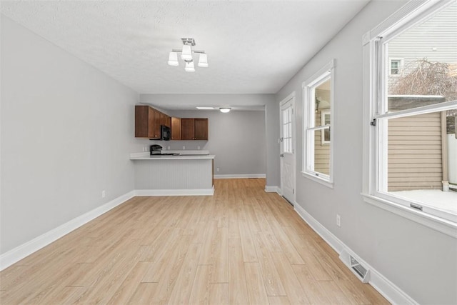 unfurnished living room with a textured ceiling and light hardwood / wood-style flooring