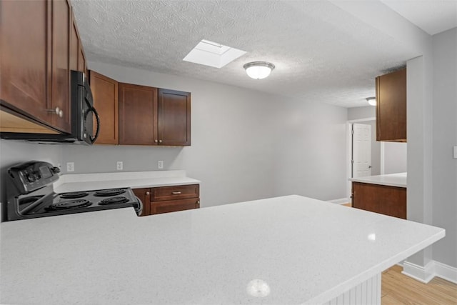 kitchen with kitchen peninsula, a textured ceiling, a skylight, and electric stove