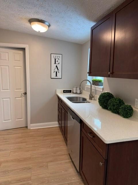 kitchen featuring dark brown cabinetry, dishwasher, sink, light hardwood / wood-style flooring, and a textured ceiling