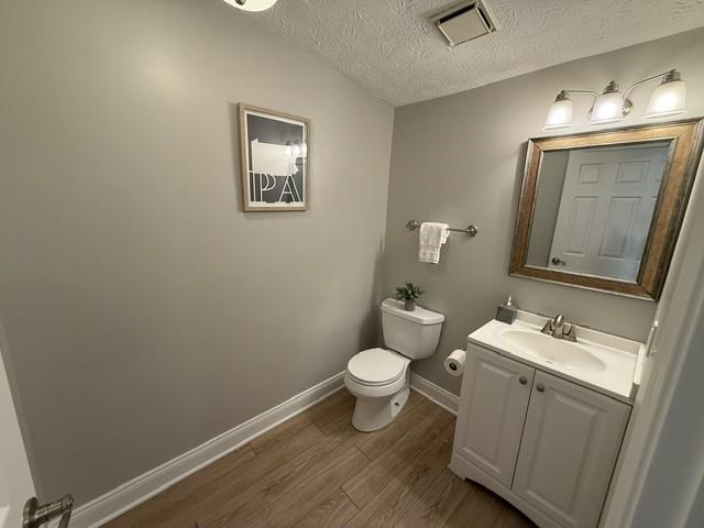 bathroom with hardwood / wood-style flooring, vanity, a textured ceiling, and toilet