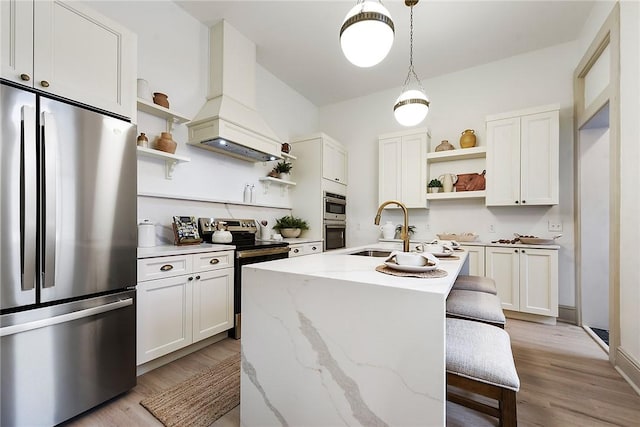 kitchen featuring stainless steel appliances, light stone counters, a center island with sink, and sink