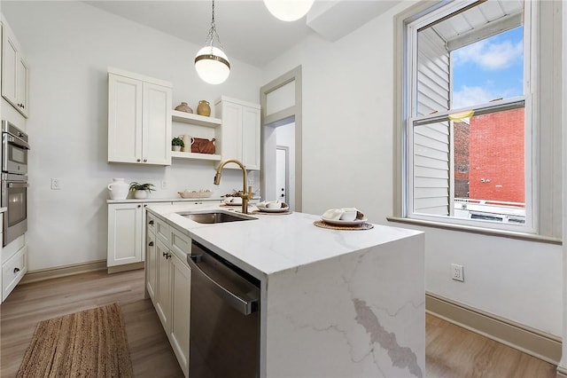 kitchen with sink, white cabinets, stainless steel appliances, and a center island with sink