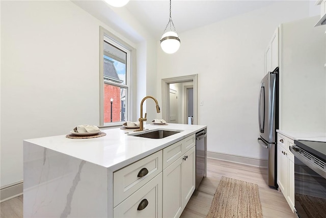 kitchen featuring white cabinetry, sink, stainless steel appliances, pendant lighting, and a kitchen island with sink