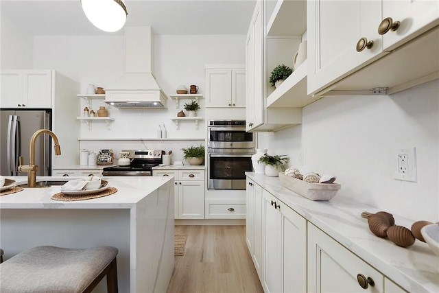 kitchen featuring a kitchen breakfast bar, light stone counters, light hardwood / wood-style flooring, appliances with stainless steel finishes, and custom exhaust hood