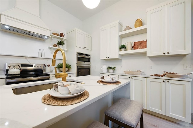 kitchen featuring premium range hood, white cabinets, a kitchen bar, and stainless steel appliances