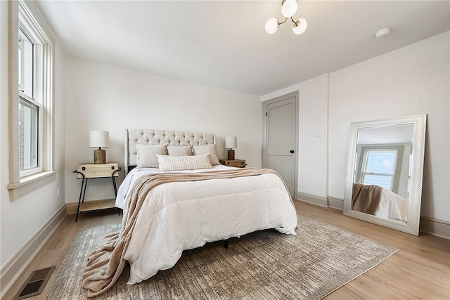 bedroom featuring a chandelier, light wood-type flooring, and multiple windows