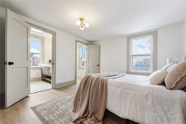 bedroom featuring ensuite bathroom and light hardwood / wood-style flooring