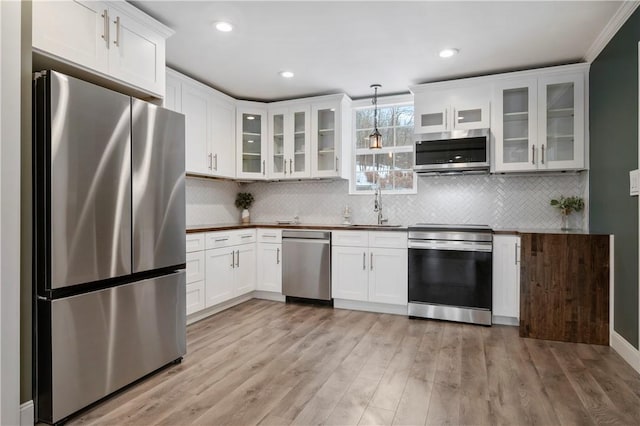 kitchen with sink, stainless steel appliances, light hardwood / wood-style flooring, decorative light fixtures, and white cabinets