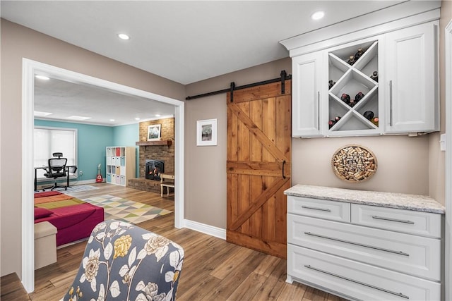 interior space featuring a wood stove, a barn door, and light wood-type flooring