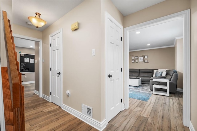 hall with ornamental molding and light hardwood / wood-style flooring