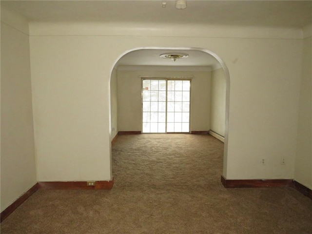 carpeted spare room with a baseboard heating unit