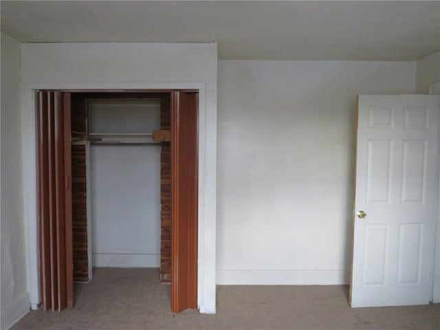 unfurnished bedroom featuring light carpet and a closet