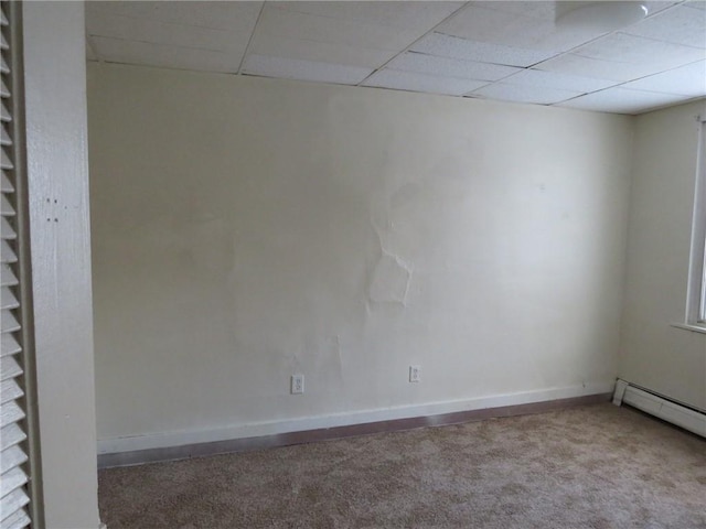 unfurnished room featuring a paneled ceiling, carpet floors, and a baseboard heating unit