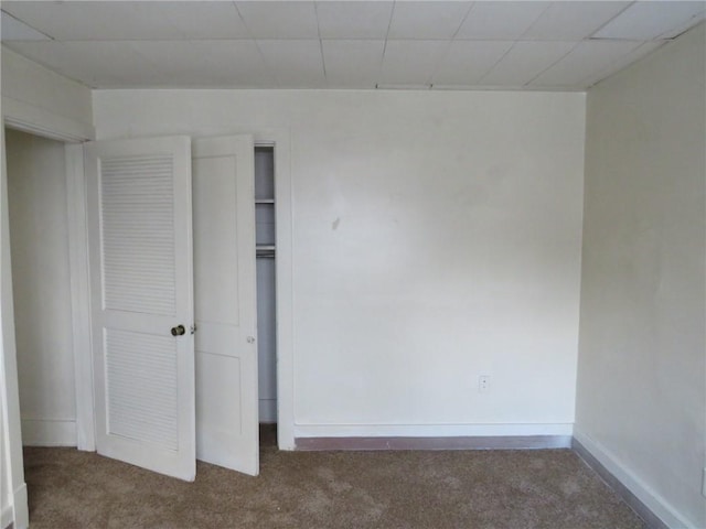 unfurnished bedroom with dark colored carpet and a closet