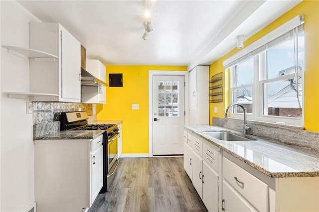 kitchen with gas stove, white cabinetry, sink, and light stone counters