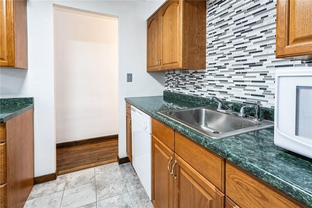 kitchen featuring white dishwasher, backsplash, light tile patterned floors, and sink