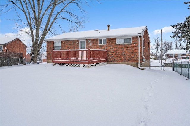 snow covered back of property with a wooden deck