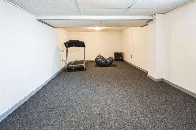 exercise room with a paneled ceiling and dark carpet