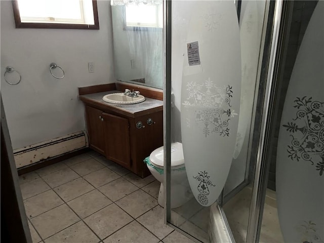 bathroom with vanity, a shower with door, tile patterned floors, toilet, and baseboard heating