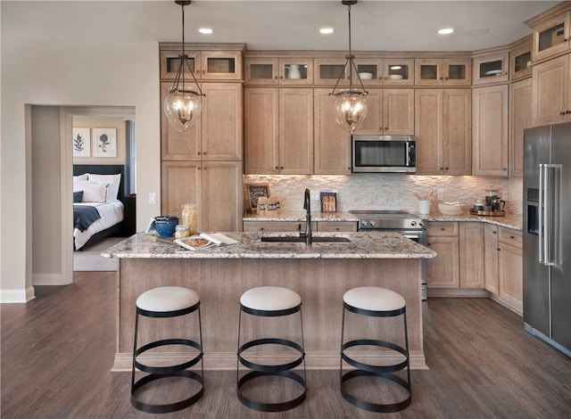 kitchen with pendant lighting, stainless steel appliances, a center island with sink, and sink