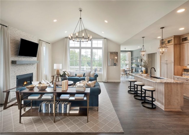 dining space featuring high vaulted ceiling, a stone fireplace, dark wood-type flooring, and sink