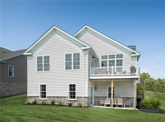 rear view of house featuring a patio area, a balcony, and a yard